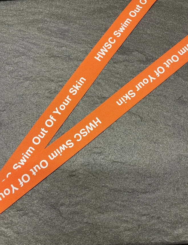 HWSC Swim Out Of Your Skin printed on an orange woven ribbon